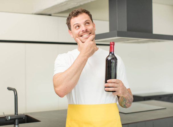 smiling with a happy, confident expression with hand on chin. bottle of wine concept - 写真・画像