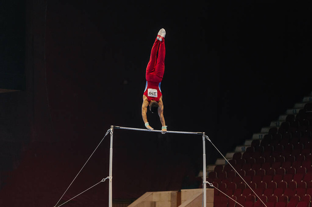 gimnasta ejercicio barra horizontal en el campeonato de gimnasia, elemento columpios colgantes largos - Foto, imagen