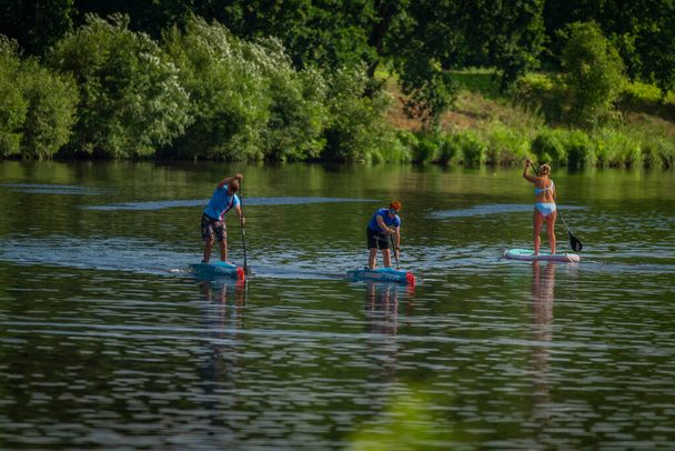 Peddelbord met sporters in de zomer zonnige dag op de Vltava rivier in Budweis CZ 07 31 2023 - Foto, afbeelding