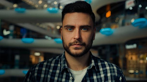 Close-up single male portrait of Caucasian bearded guy confident businessman young 30s man customer client shopper in trendy casual shirt posing confidence pose at modern shopping mall business center - Photo, Image
