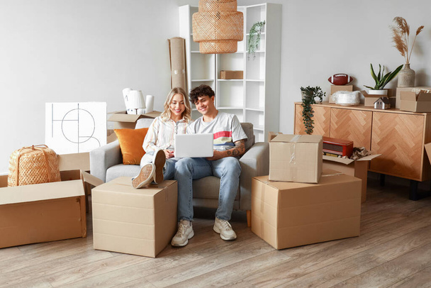 Young couple using laptop in room on moving day - Photo, Image
