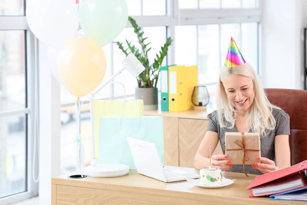 Зрелая женщина с подарком на день рождения в офисе - Фото, изображение