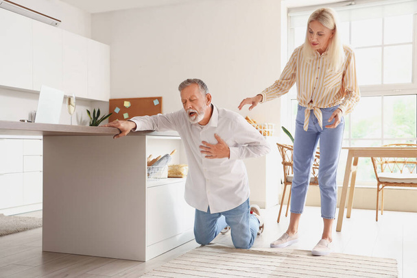 Mature woman and her husband having heart attack in kitchen - Photo, Image