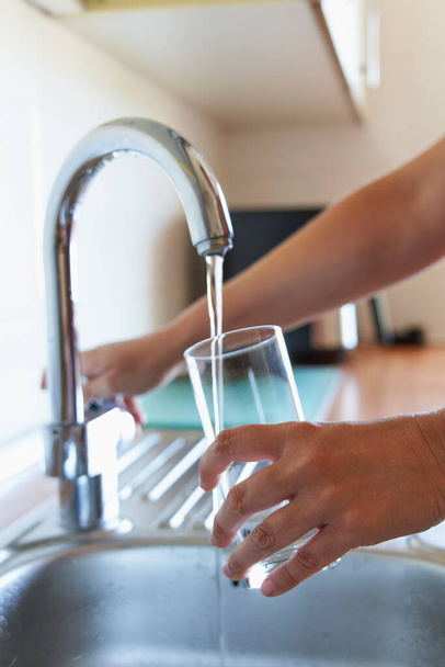 Vrouw vullen glas koel water bij keukenkraan - Foto, afbeelding