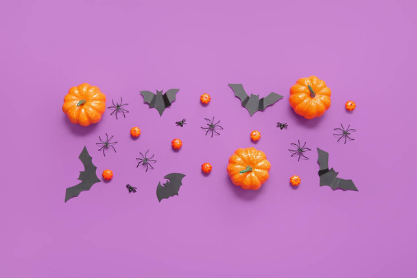 Komposition mit Kürbissen, Papierfledermäusen und Spinnen auf violettem Hintergrund. Konzept zur Halloween-Feier - Foto, Bild