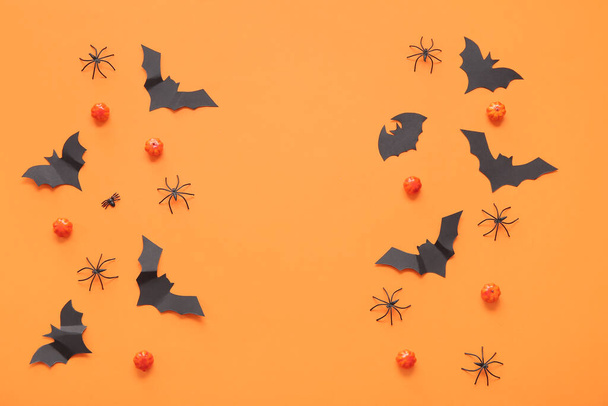 Composition with pumpkins, paper bats and spiders on orange background. Halloween celebration concept - Photo, Image