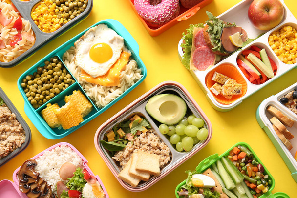 Many lunchboxes with different delicious food on yellow background - Photo, Image