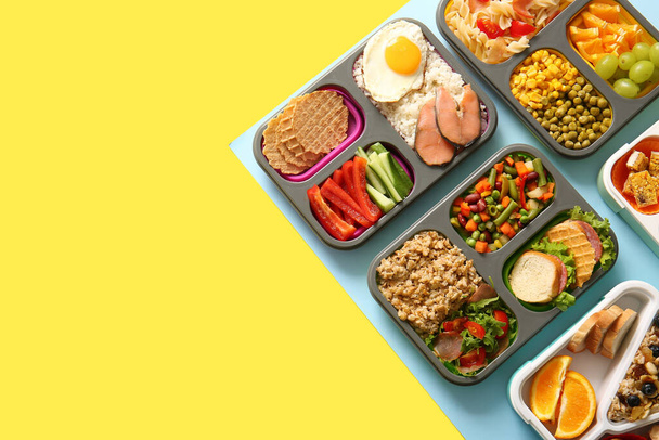 Veel lunchboxen met verschillende heerlijke gerechten op kleur achtergrond - Foto, afbeelding