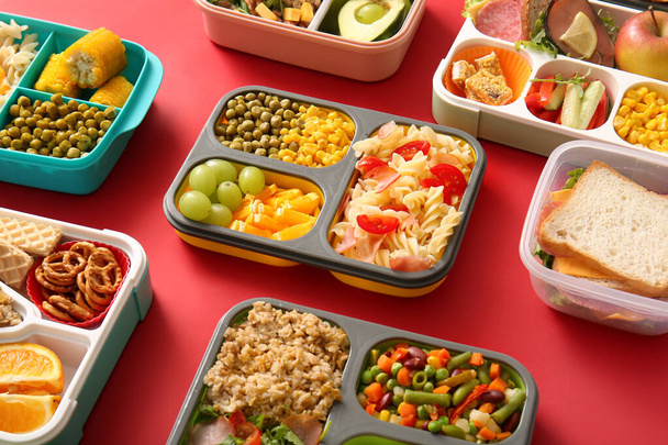Wiele pudełek śniadaniowych z różnych pyszne jedzenie na czerwonym tle - Zdjęcie, obraz