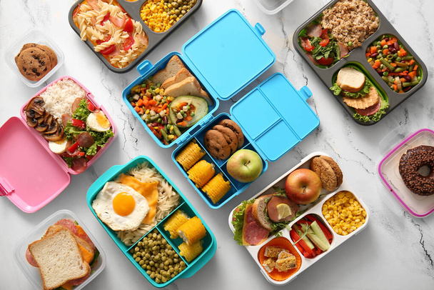 Многие обеденные коробки с различными вкусными блюдами на гранж белом фоне - Фото, изображение