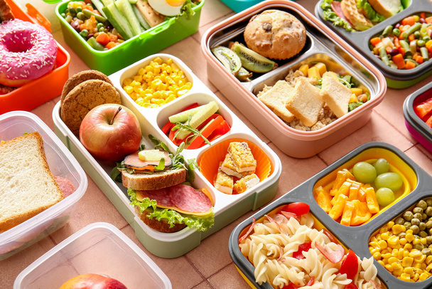 Many lunchboxes with different delicious food on pink tile background - Photo, Image