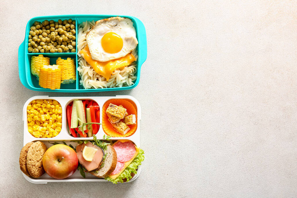 Lunchboxen met verschillende heerlijke gerechten op lichte achtergrond - Foto, afbeelding