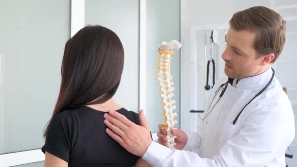 Een jonge vrouw wordt onderzocht door een vertebroloog. Een professionele arts onderzoekt de rug, palpeert de ruggengraat van de patiënten. Preventie van scoliose en osteochondrose - Video