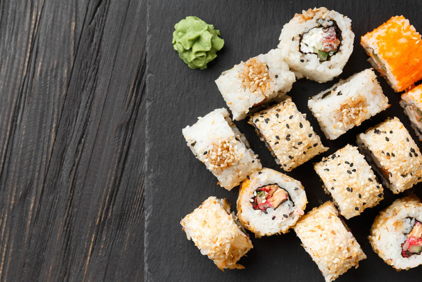 Set di involtini di sushi con salmone, tonno, caviale, semi di sesamo su un piatto di ardesia nera, primo piano. - Foto, immagini