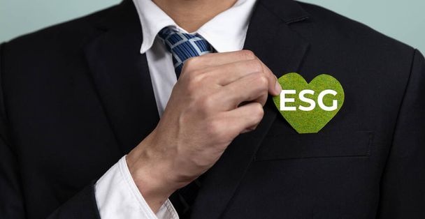 Corporativo promoviendo el concepto de negocio sostenible y verde con el empresario sosteniendo el papel de símbolo de ESG como compromiso del gobierno social ambiental usando energía limpia con cero emisiones de CO2. Alteración - Foto, Imagen