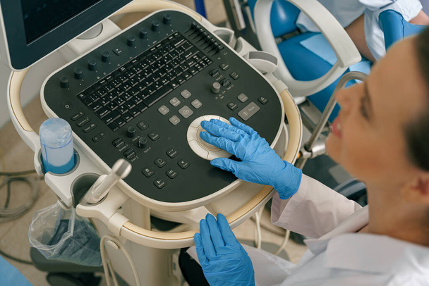 Médecin échographe femelle appuyant sur les boutons du panneau de commande à ultrasons. Photo de haute qualité - Photo, image