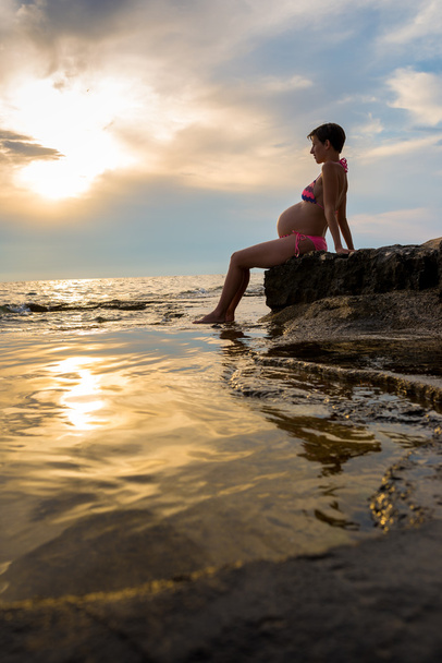 Terhes nő ül a parton - Fotó, kép