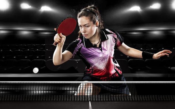 Young pretty sporty girl playing table tennis on black background. Action shot. - Fotó, kép