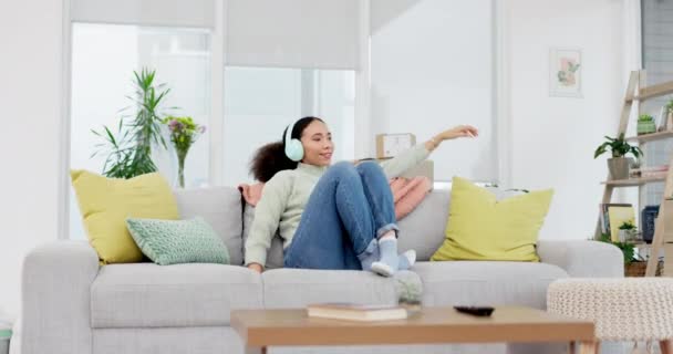 Music, headphones and woman relax on a sofa with radio, streaming or playlist in her home. Podcast, earphones and female person in a living room with audio, resting and chilling with weekend freedom. - Footage, Video