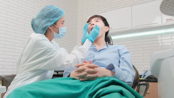 Asiatische Zahnärztin untersucht junge männliche Patientenzähne und Zahnschmerz-Stomatologie in Zahnklinik, Gesundheitshygiene-Checks und professionelle kieferorthopädische Gesundheitsarbeit in Arztpraxis-Krankenhaus. - Filmmaterial, Video