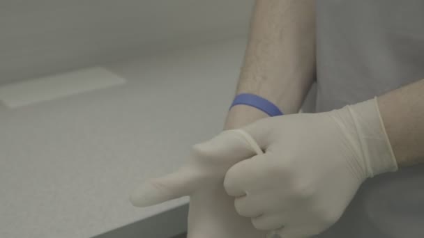 Un trabajador médico se pone guantes de látex. Las manos de un hombre. Primer plano. Una clínica moderna. Medicina. Clínica auténtica - Imágenes, Vídeo