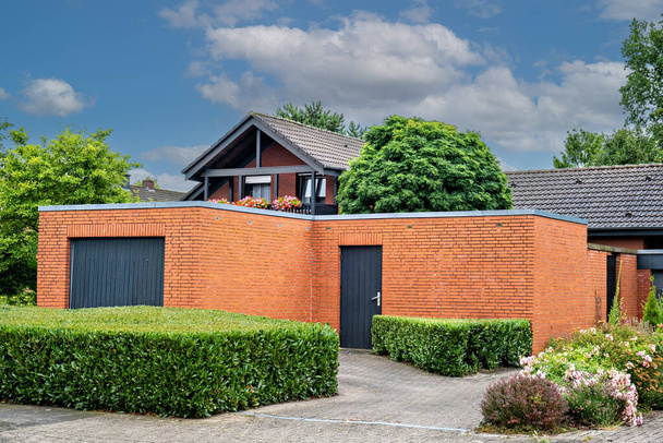 Una casa di mattoni rossi con una porta grigia garage in Germania. - Foto, immagini