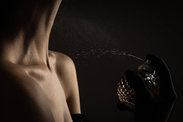 Młoda kobieta stosująca perfumy na czarnym tle, zbliżenie - Zdjęcie, obraz
