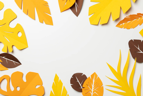 Papel amarillo y marrón hojas tropicales sobre un fondo claro - Foto, Imagen