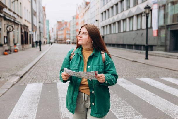 Glückliches Touristenmädchen mit Landkarte reist durch Europa. Urlaubskonzept durch die Erkundung interessanter Reiseziele. Frau sucht Orte - Foto, Bild