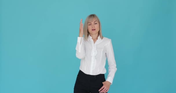 A distressed woman is seen facepalming in frustration on a serene blue background. Her troubled expression and hand gesture indicate her feeling of disappointment or exasperation. - Footage, Video