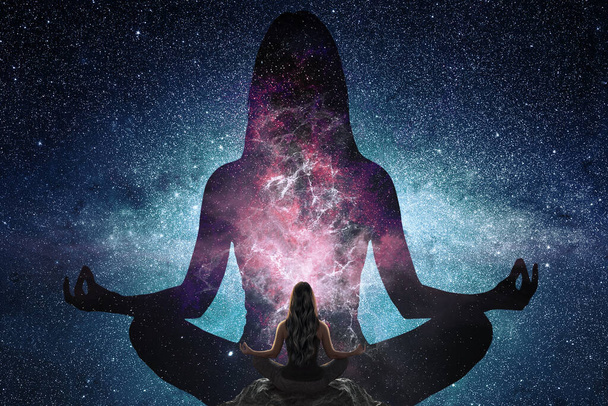 Woman doing yoga in front of silhouette of woman in the universe - Photo, Image