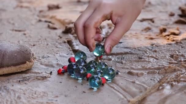 Uma mão de criança brincando com mármores na areia - Filmagem, Vídeo