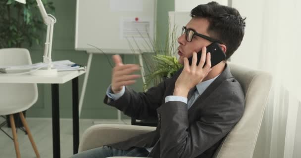 Empresário é mostrado conduzindo negociações enquanto sentado em uma cadeira de escritório. Com um comportamento compacto e bom, ele se envolve na discussão com uma abordagem de negócios. - Filmagem, Vídeo