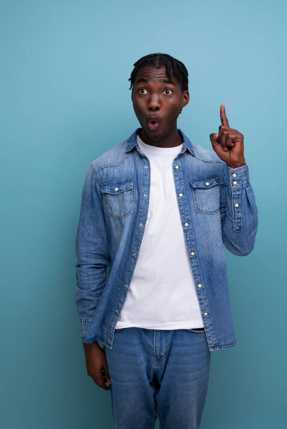 portrait of a surprised young cheerful american man with dreadlocks in a denim jacket. - Foto, imagen