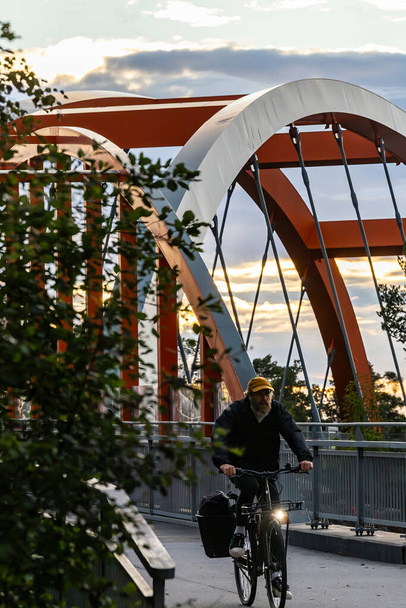 Stockholm, Sweden Aug 10, 2023 A man bicycles across a bridge on a bike path in the Vastberga distrct. - Photo, Image