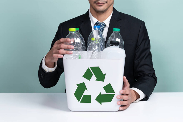 Бізнесмен тримає ковпачок, наповнений пластиковою пляшкою на ізольованому фоні. Корпоративна відповідальність за екологічне середовище та громаду. Розділення та управління відходами. Змінити
 - Фото, зображення