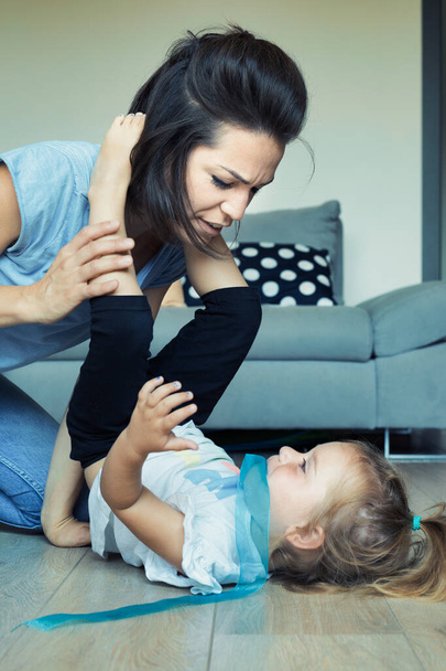 Anya és lánya fizikai játéka a nappaliban: mászás, repülés, vidáman tanulás, szeretettel és kihívásokkal teli - Fotó, kép