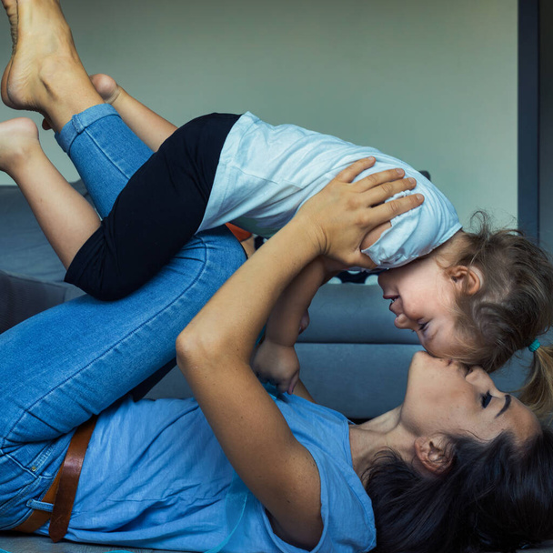 Mamá e hija, manos y pies volando en un juego alegre; aprendiendo límites físicos y emocionales en un hogar amoroso - Foto, imagen