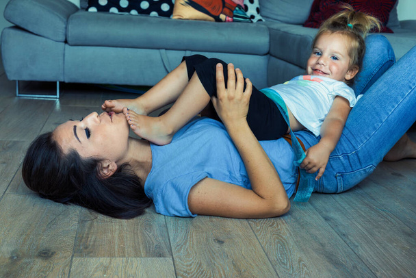 Hrací doba matky a dcery v obývacím pokoji je plná lezení, zápasení a učení. Jejich pouto roste, jak testují limity v láskyplném prostředí - Fotografie, Obrázek