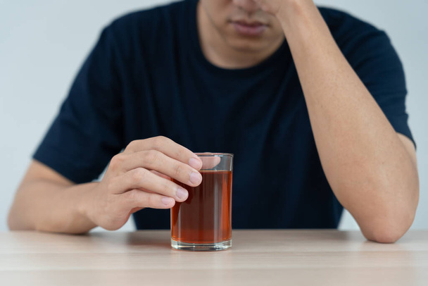 Депрессивный молодой азиат, который чувствует себя плохо, выпивая виски один дома, подчеркивает, что одинокий одинокий алкоголь страдает от проблем с алкоголем, алкоголизмом, жизнью и семейными проблемами - Фото, изображение
