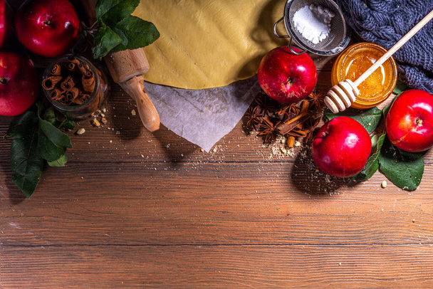 Apfelkuchen kochen Hintergrund. Herbstkuchen, Plätzchen, Tortenbackhintergrund mit Äpfeln, Gewürzen, Honig und rohem Teig, Zutaten für süßes Herbstgebäck, auf hölzernem Hintergrund Kopierfläche - Foto, Bild