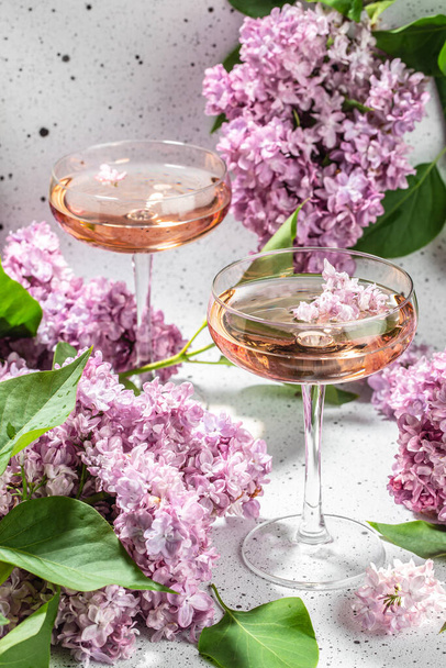 Rose wine in glass with blooming lilac on a light background, - Photo, Image