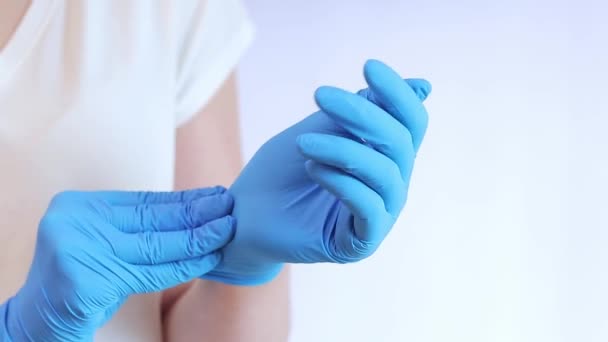 Manos en guantes médicos de látex. El médico pone guantes de goma azul en las manos sobre un fondo claro, de cerca. El concepto de medicina y salud. Médico o enfermero con guante protector de nitrilo - Metraje, vídeo