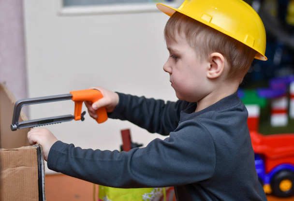 Мальчик играет с игрушечными инструментами. Ребенок серьезный и сосредоточенный - Фото, изображение