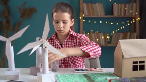 Ecología, tecnología y concepto de ahorro energético. Linda chica crear proyecto de modelos 3D de aerogeneradores y casa ecológica en su casa. Copiar espacio - Imágenes, Vídeo