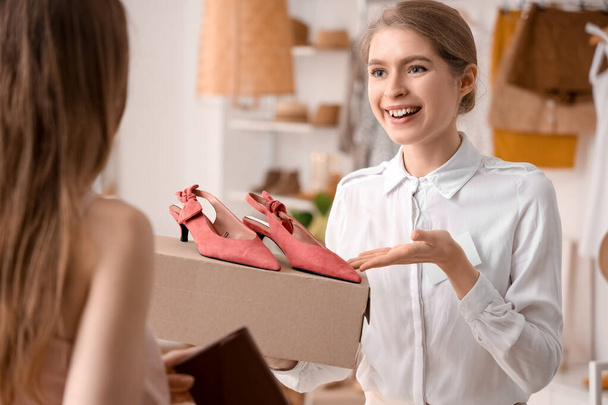 Butikteki müşterilere şık ayakkabılar gösteren kadın satıcı. - Fotoğraf, Görsel