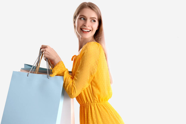 junge Frau mit Einkaufstaschen auf hellem Hintergrund - Foto, Bild