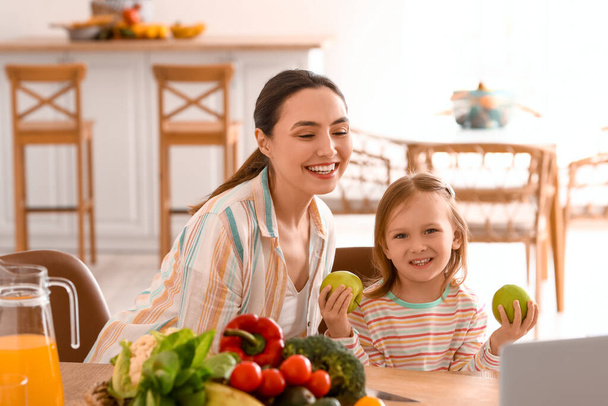 Κοριτσάκι με τη μητέρα της και μήλα στην κουζίνα. - Φωτογραφία, εικόνα