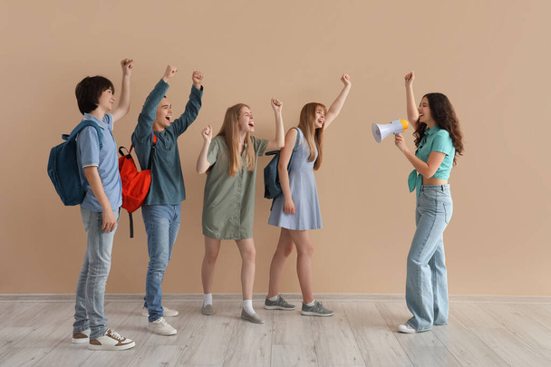 Studentengruppe mit Megafon brüllt nahe beiger Wand - Foto, Bild