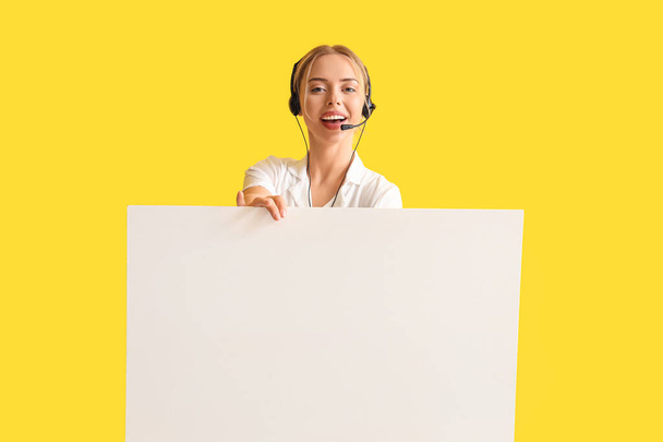 黄色の背景に空白のポスターを持つ女性技術サポートエージェント - 写真・画像